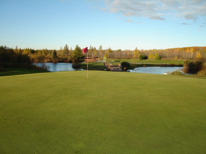 Golf course green with pond in distance